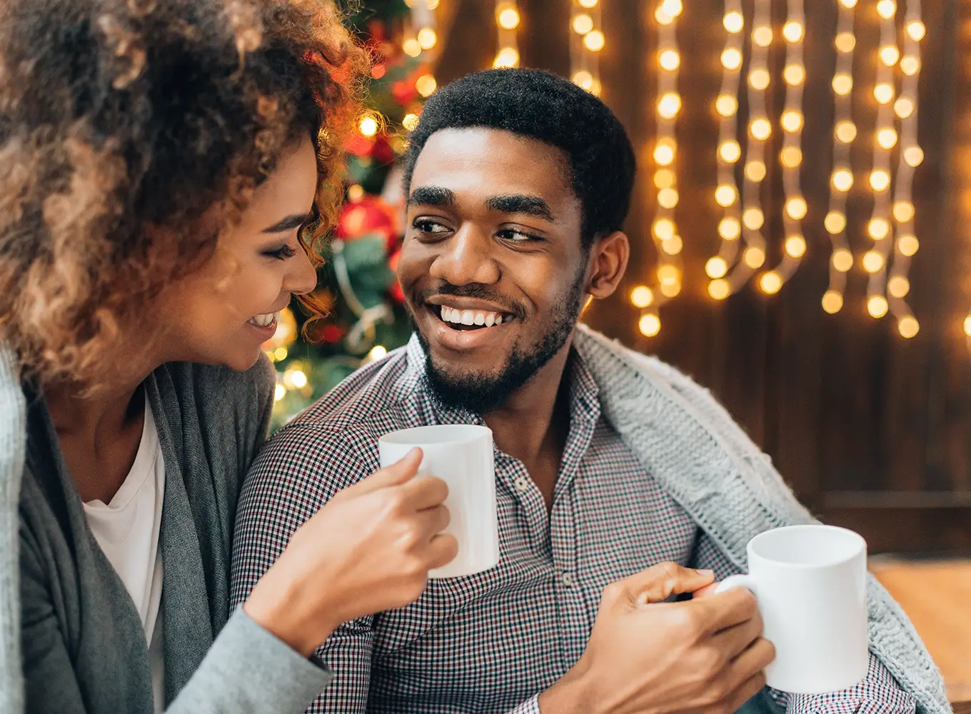 young couple enjoying their cups of coffee while sitting in their warm and cozy living room